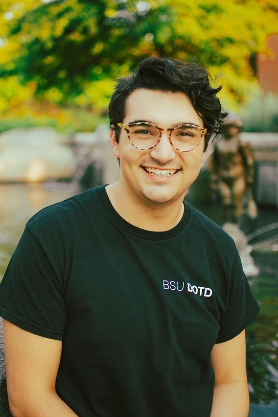 A portrait of Brenden Rowan, lighting designer, in front of a fountain at Ball State University in Muncie, Indiana